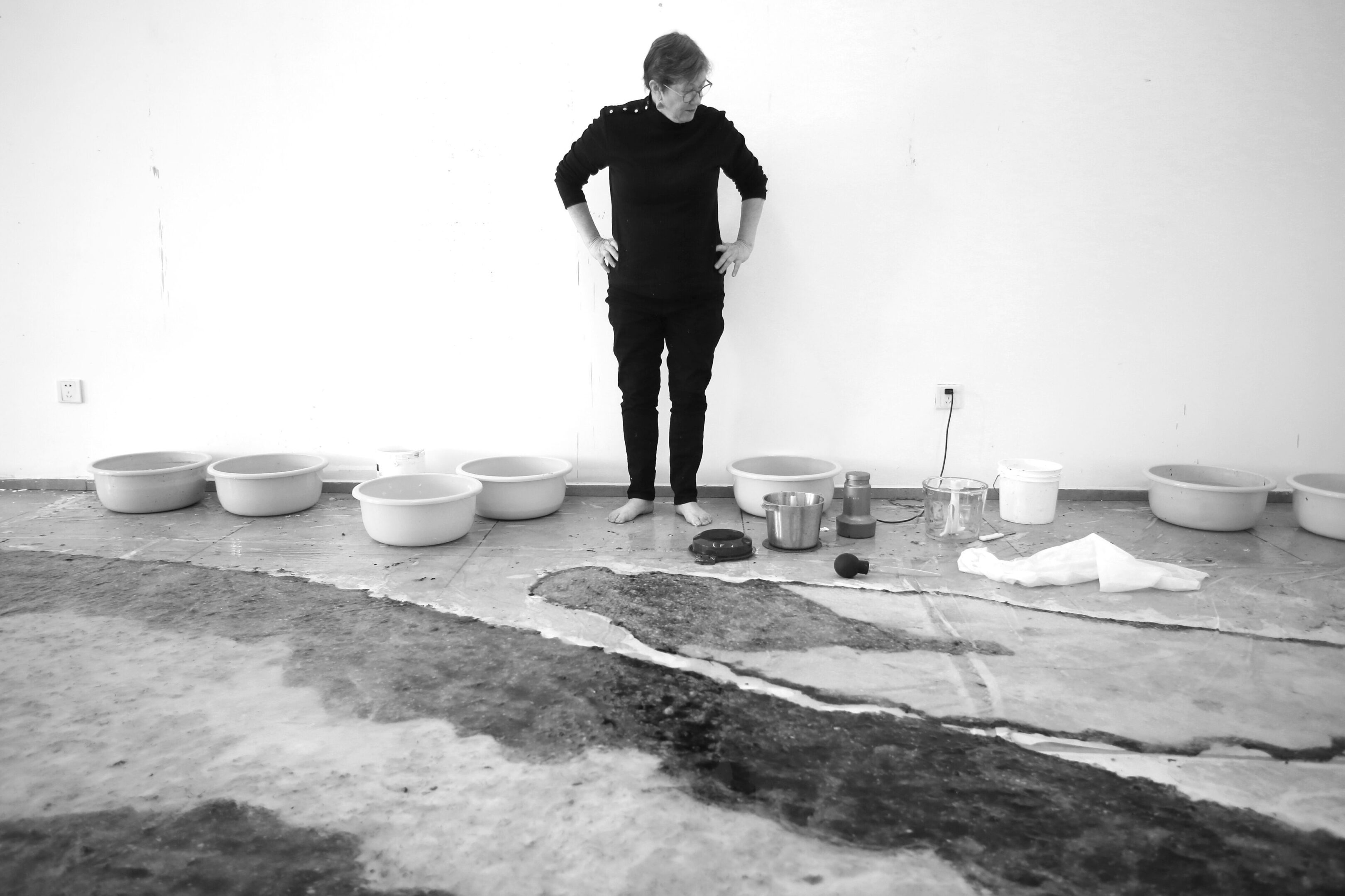 Artist looking at buckets and stained ground.